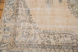 Distressed corner of vintage Sparta rug, with faded ocean green blue cartouche motifs and visible foundation.