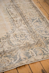 Distressed vintage Sparta rug, showing even wear and decorative ivory, gold, green-blue motifs.