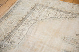Close-up of vintage distressed Sparta carpet corner showing textured wear, faded ivory and sand hues.