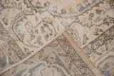 Folded corner of distressed hand-knotted Sparta carpet, showing worn pile, foundation, and faded ivory.