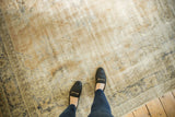 Artfully distressed vintage Oushak carpet showcasing faded patterns and worn texture underfoot.