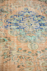 Vintage distressed Oushak rug with apricot orange, blue, and green Rococo florals and even wear.