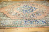 Distressed vintage Oushak carpet showing worn apricot field, royal blue border, and Rococo floral motifs.