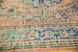 Distressed Oushak carpet with rococo floral designs in apricot, sea foam green, and royal blue.