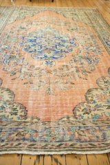 Distressed Oushak rug border and fringe with tangerine, royal blue, sea foam floral motifs.