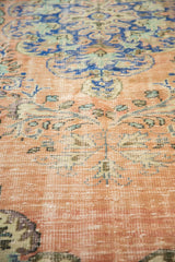 Distressed pile texture and rococo floral motifs in tangerine, blue, and green on vintage Oushak.