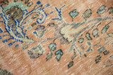 Distressed texture of vintage Oushak rug with tangerine, blue, and green rococo floral detail.