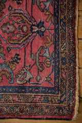 Vintage Lilihan rug's raspberry red field with delicate vinery and a rich navy border.
