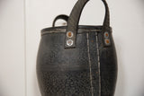 Textured recycled rubber basket handle with rusted rivets and white stitching.