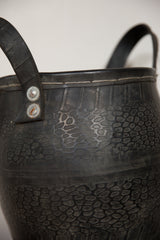 Detailed view of the dark rubber basket's pebble texture, top stitching, and metal rivets.