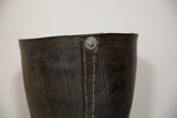 Detail of dark recycled tire rubber showing ribbed texture, white stitching, and metal rivet.