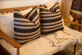 Two reclaimed remnant pillows with onyx black basket weave stripes and natural bands.