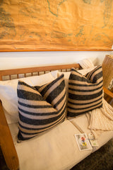 Reclaimed onyx black and natural striped pillow, cream knit blanket, and product tags.