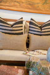 Textured natural jute pillow detail with a black and jute striped pillow behind.