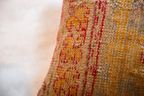 Handwoven texture of antique rug fragment pillow with orange, red, and beige threads.