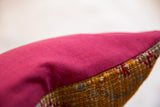 Textured edge of the antique Turkish rug fragment pillow with bright raspberry red backing.