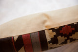 Kilim rug fragment pillow showing dark brown, beige, red geometric pattern and cream fabric.