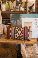 Left side detail of antique kilim lumbar pillow, featuring rich striped and geometric patterns.