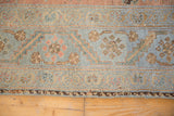 Distressed vintage Malayer rug border featuring intricate slate blue-grey and terra cotta patterns.