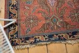 Vintage Lilihan rug corner with dusty cochineal red field, navy border, and tattered fringe.