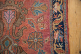 Close-up of vintage Lilihan rug's dusty cochineal red field, blossomed floral motifs, and navy border.