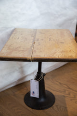 Distressed reclaimed wooden end table's top showing faded sage cream paint and crack.