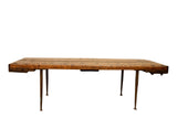 Reclaimed wood table featuring a long, textured top and slender needle legs.