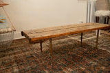 Reclaimed wooden table top with rustic texture and slender needle legs.