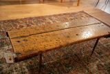 Reclaimed wooden table top showing visible surface texture and dark needle leg.
