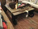 Black Cart Coffee Table's industrial design, large wheels, and light wood top.