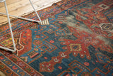 Prominent foundation wear across navy blue and cherry red geometric patterns of antique Hamadan rug.