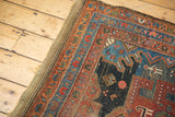 Geometric red, blue, and orange borders on antique Hamadan rug with visible pile wear.