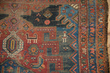 Antique Hamadan rug's tribal geometric patterns, stylized figures, and rich cherry red and navy blue.