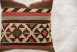 Close-up of the reclaimed kilim pillow showing bold geometric stripes in brown, red, and grey.