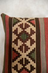 Hand-woven kilim pillow featuring geometric earth tone, red, and green stepped patterns.