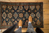 Vintage Lilihan rug's Veramin floral lattice in midnight blue, blush, and bronze, with feet.