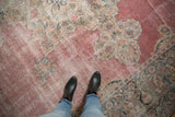 Worn, low-pile texture on the faded raspberry pink field of an antique Kermanshah carpet.