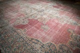 Low-angle view of the antique Kermanshah rug showing its distressed, time-softened texture.