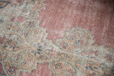 Evenly worn pile of an antique Kermanshah carpet with faded pink and ivory Rococo outlines.