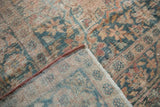 Corner view of the distressed antique rug, folded to show its hand-knotted foundation and secured side.