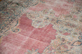 Rococo style medallion details against the worn raspberry pink field of an antique Kermanshah carpet.