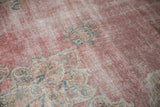 Angled detail of the distressed Kermanshah's low pile showing time-softened wear and faded floral motifs.