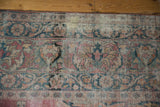 Close-up on the distressed border of an antique Kermanshah carpet showing wear down to the knot heads and foundation.