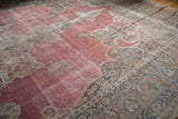 Angled view of the antique Persian carpet's distressed texture and intricate border.