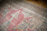 Angled view of the antique Kermanshah carpet's intricate floral border and time-softened texture.