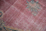 Distressed raspberry pink field of an antique Kermanshah carpet showing low pile worn to the knot heads.