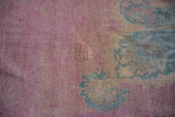 A rewoven piled area on the faded raspberry pink field of an antique Persian carpet.