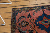 Vintage Lilihan rug corner with dramatic navy scrolling leaves on a blush field.