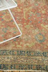 Mostly even wear across the hand-knotted pile of an antique Persian runner in rust, green, and navy.