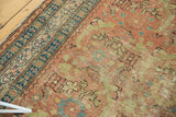 Detailed view of an antique Persian runner's navy border and rust-colored field with pale green Herati motifs.